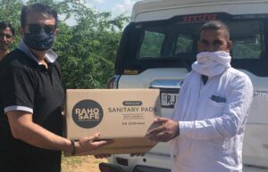 Vikas-Bagaria-handing-over-a-box-of-Raho-Safe-sanitary-pads-to-the-Sarpanch-of-a-village-in-Rajasthan.